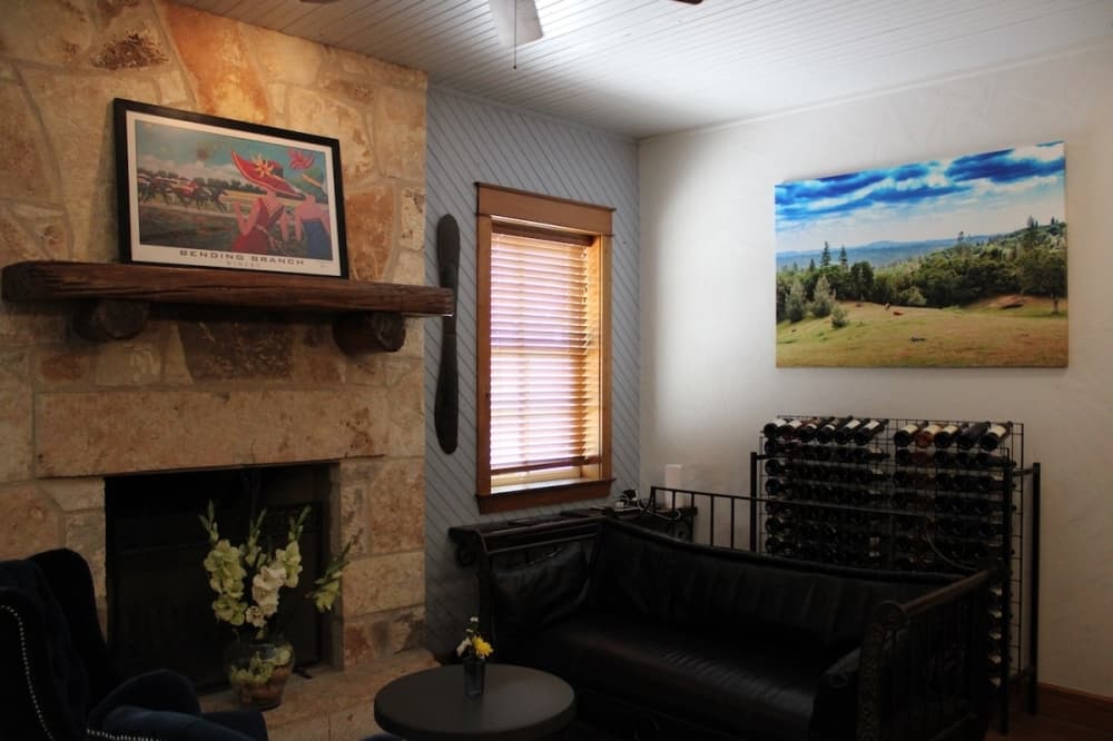 A living room with a rack of wine, a fireplace and a fouton.