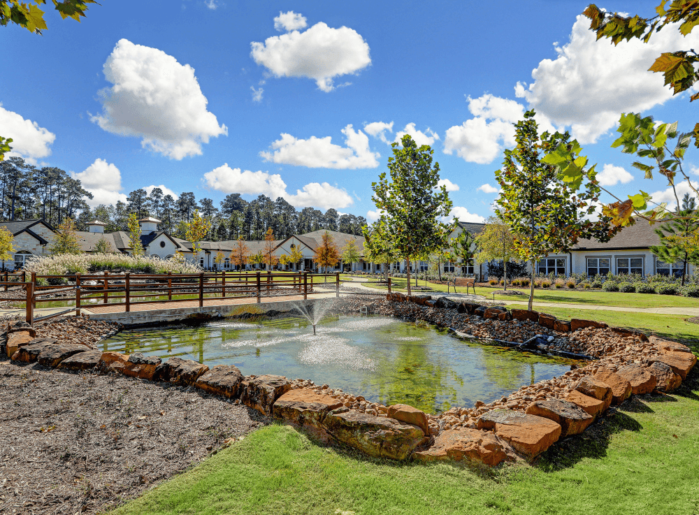 Secure courtyard with walking paths and outdoor seating at Woodhaven Village senior community in Conroe. 