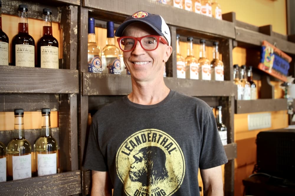 Image of founder Scott Calame standing in front of his bottle display in the lounge 