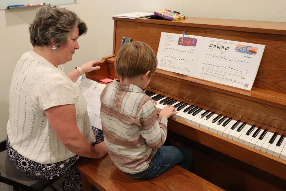 a child and an adult playing the piano 