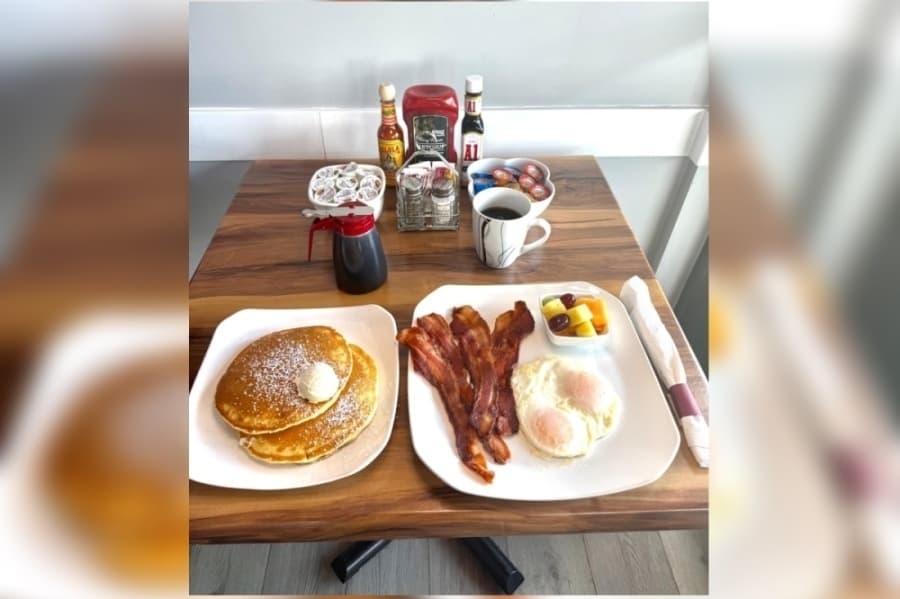 image of a table set with coffee, pancakes, eggs and bacon