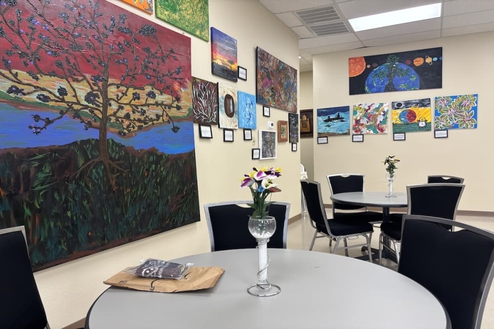 Tables with a wall of paintings behind them in an art studio.