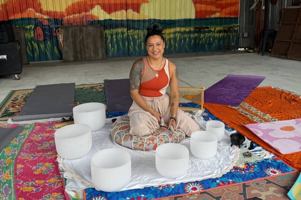 Female sitting on a tufted floor pillow with white bowls in a semi-circle arrangement in front of her.
