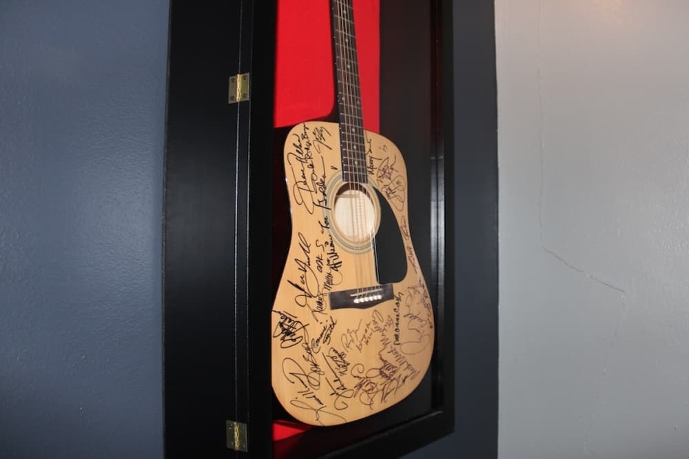 A guitar inside a glass case that is covered with signatures.