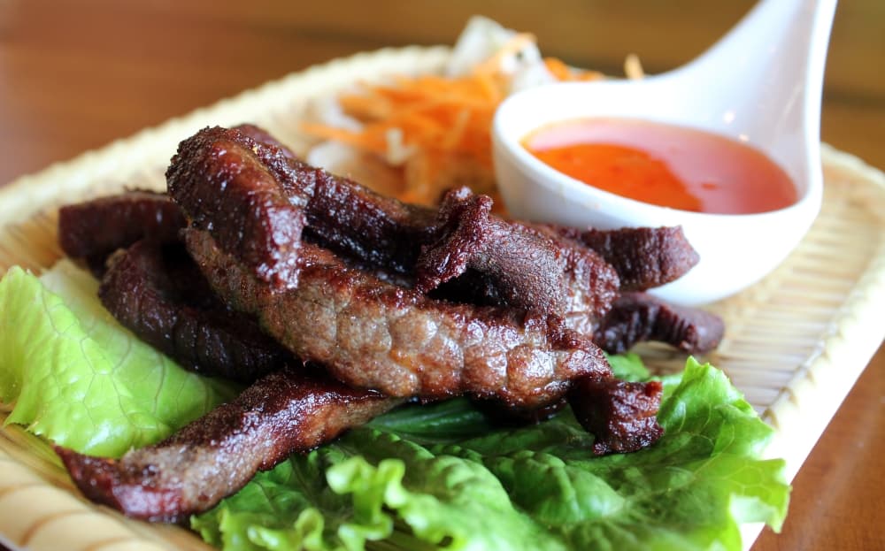 Strips of meat on lettuce with a side of orange dipping sauce. 