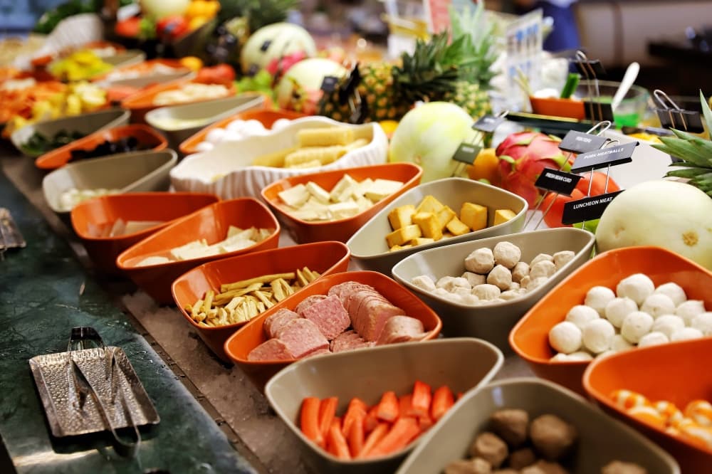 Individual dishes of vegetables and meat on a buffet. 