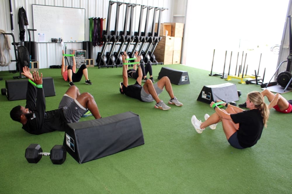 Group of people using resistance bands while lying on an astroturf-covered floor. 