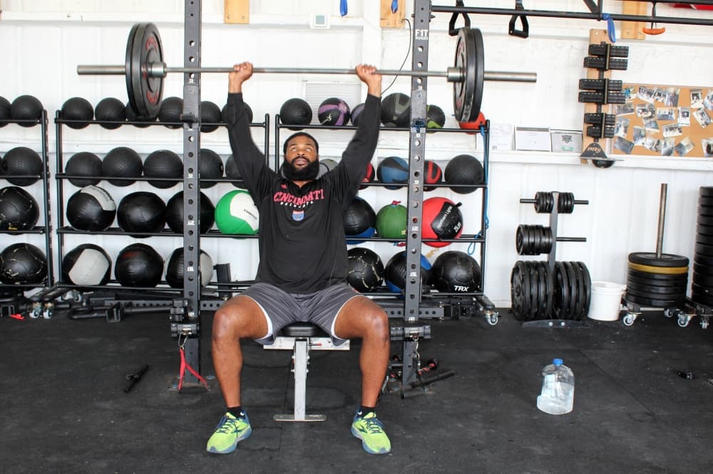 Male lifting barbell from a seated position. 