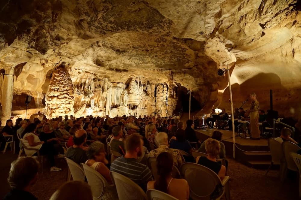people sit in a cave and listen to a person on stage