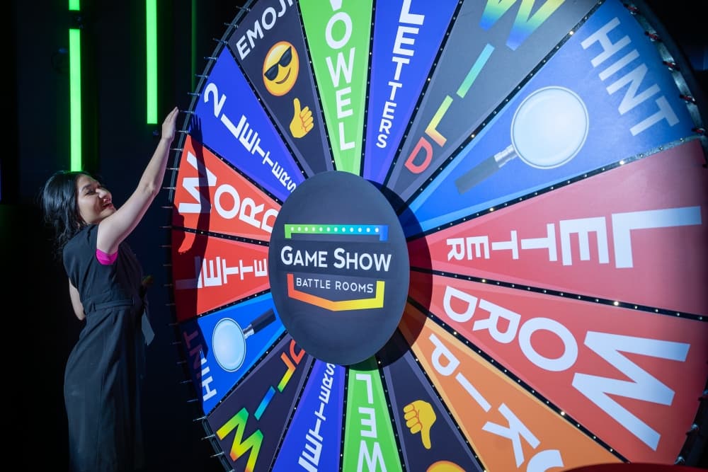 Guests spinning the giant wheel in Spin and Solve at immersive game show entertainment center near Houston.
