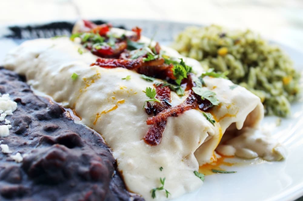 Chicken enchiladas with sides of beans and rice. 