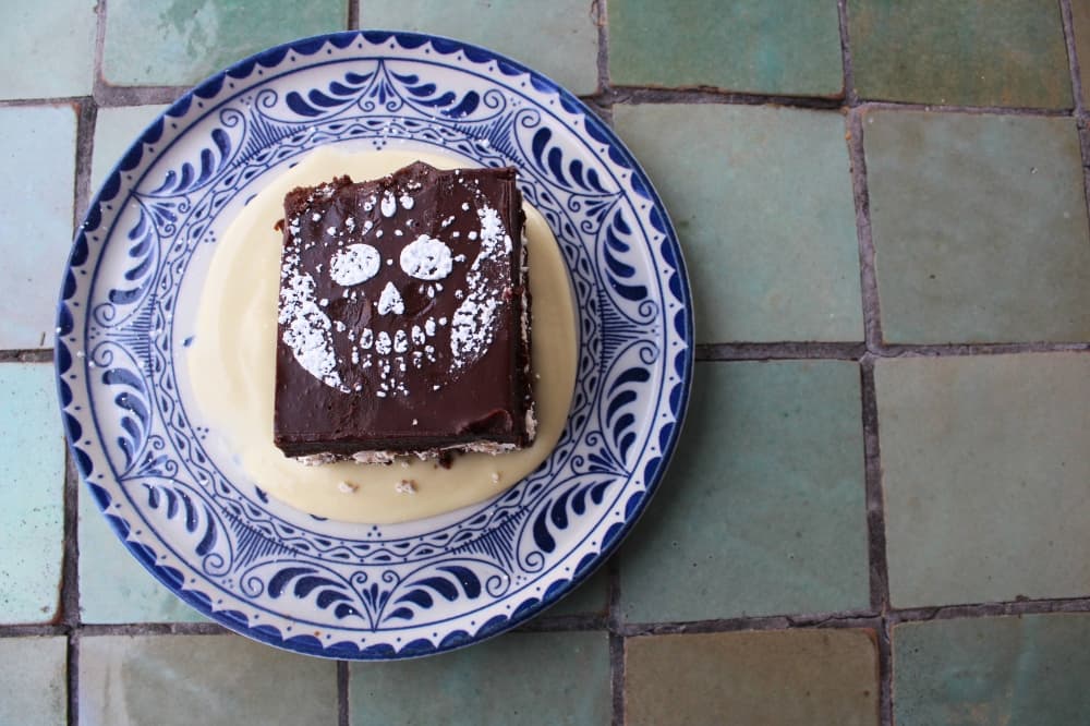 Overview of a piece of chocolate cake with topped with powder sugar stencil of sugar skull.