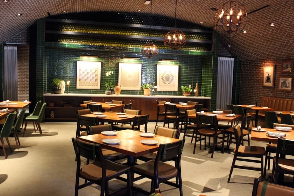 Dining room in a restaurant featuring green and brown design elements. 
