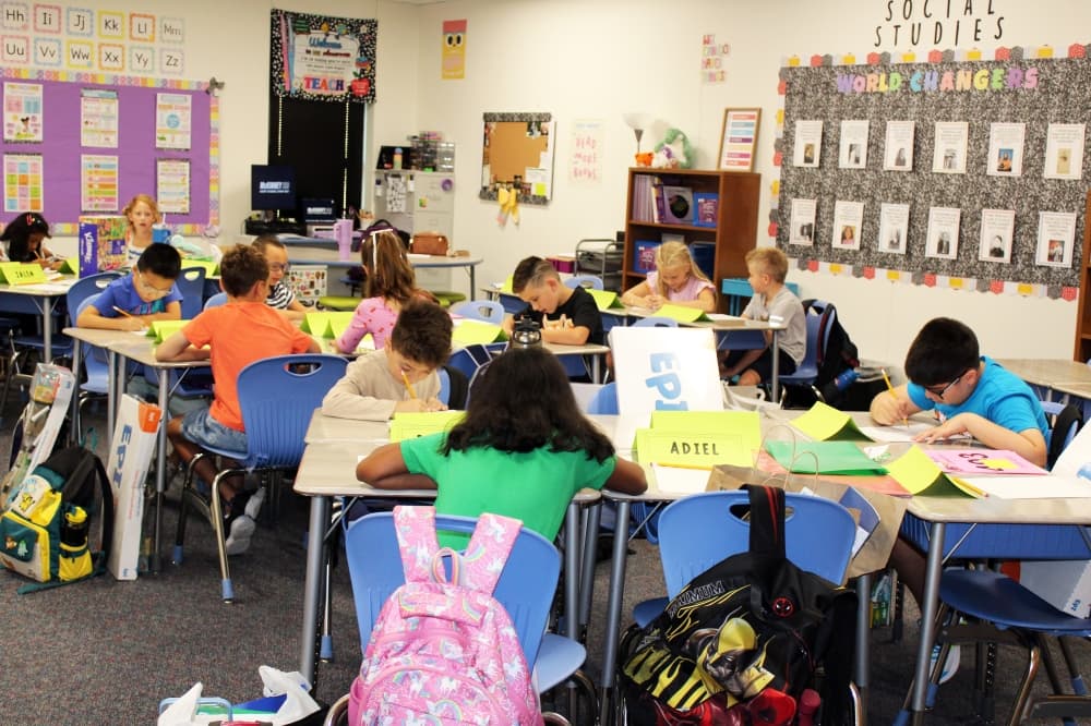 Elementary-aged children working at desks in a classroom. 
