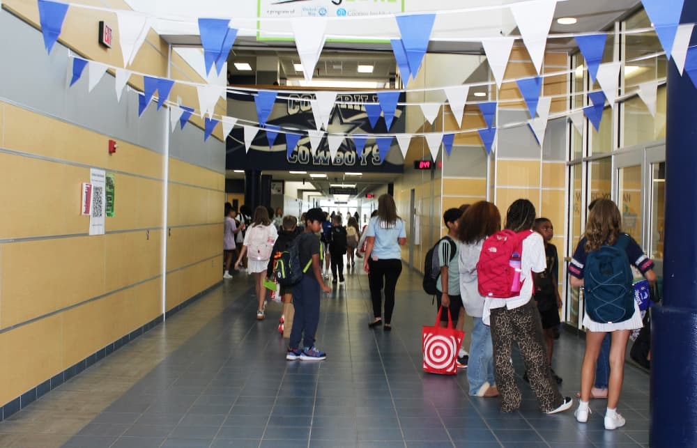 Students walking through school hallways decorated with blue and white pennant banners. 