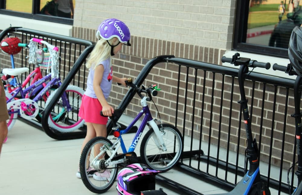 Young girl putting her bike on a bike rack. 
