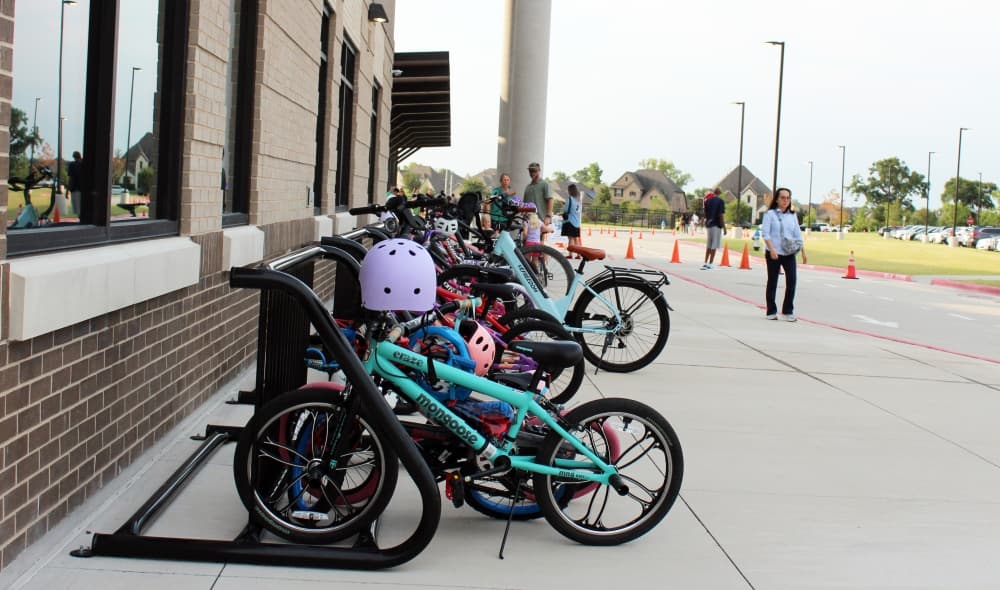 Small bikes lined up in a bike rack. 