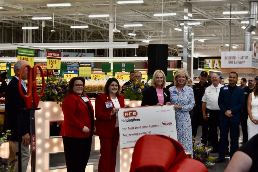 a group of people smile while holding a large cheque