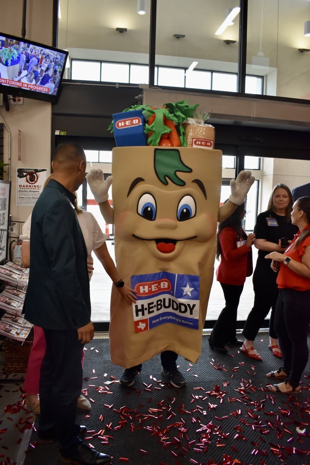 a grocery bag mascot waves its hands