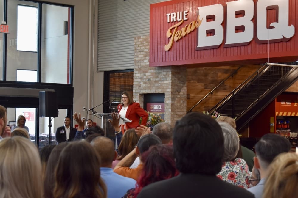 a woman speaks to a crowd in a grocery store