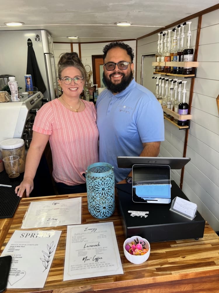 a couple smiles behind a register
