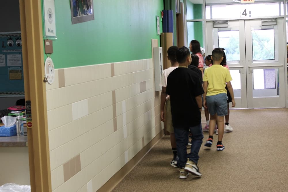 Students are in a single-file line in the hallway as they move to a different classroom
