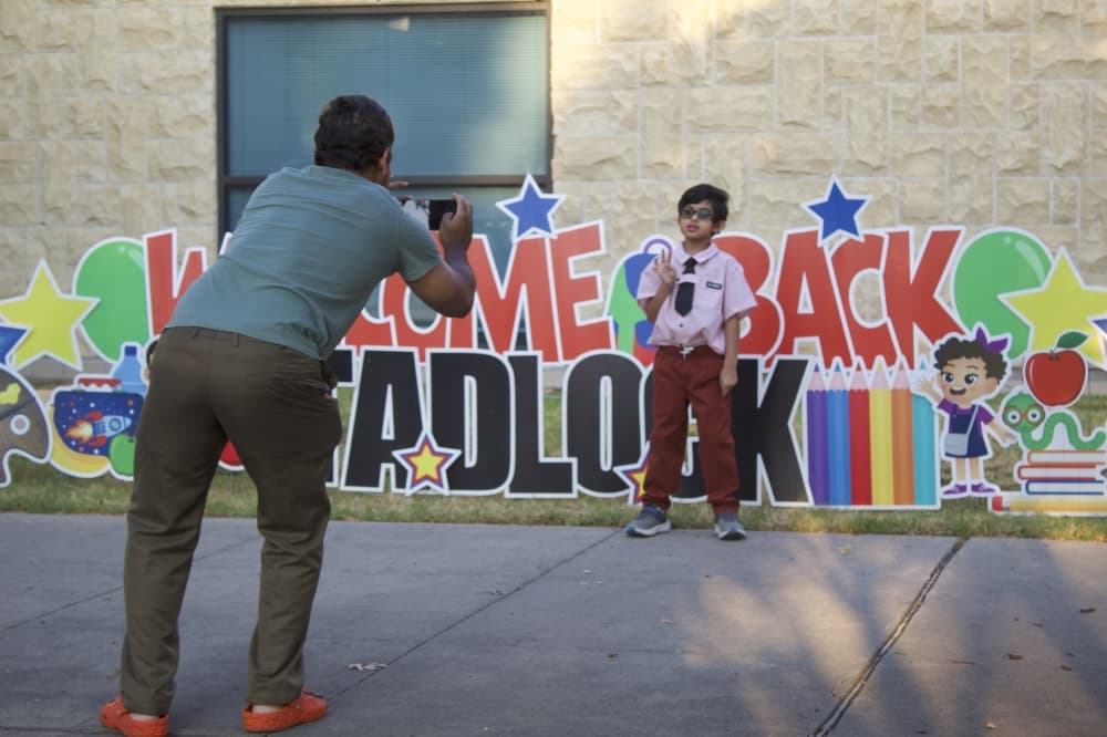 Parents take photos of their children at a Welcome back sign at Tadlock Elementary School. (Samantha Douty/Community Impact)