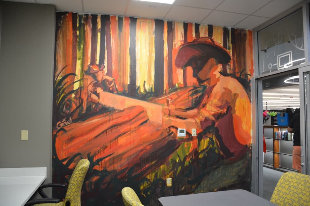 A Piney Woods-inspired mural by Gael Giovani Guardado is painted on a wall within a study room inside the library.