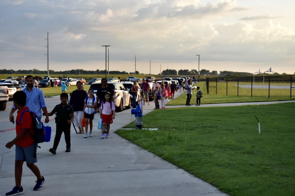 several groups of families walk down a sidewalk