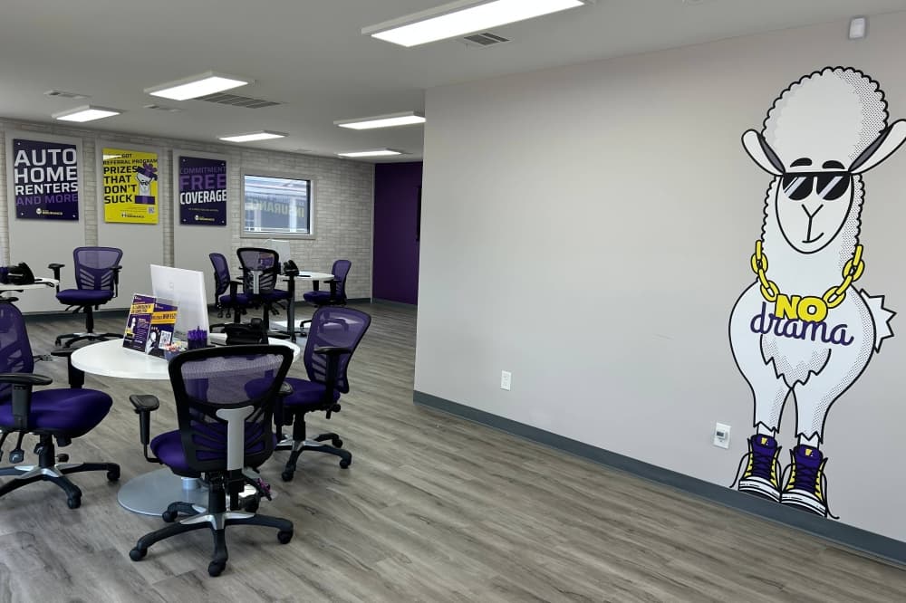 Interior of a business with a tables and chairs placed around a room and a llama graphic element on a wall. 