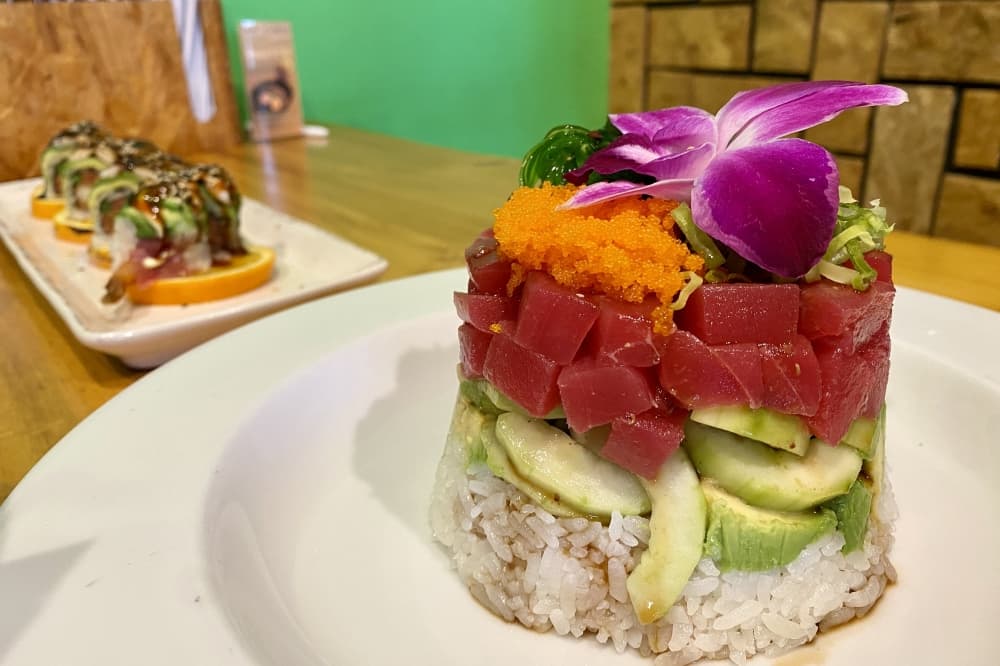 In addition to ramen, the resturant also serves sushi and poke. The flaming tiger roll is served on fire with spicy tuna, shrimp tempura, steamed asparagus and crunchy flakes topped with ebi shrimp, layered avocado, kewpie mayo, siracha, sweet soy and furikake ($21.00). (Katlynn Fox/Community Impact)