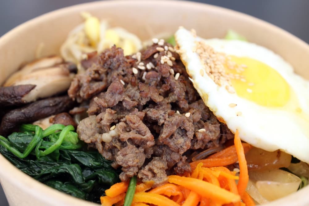 Meat, dumplings, egg and vegetables in a bowl. 