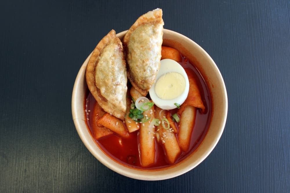 Noodles in a red sauce topped with two dumplings. 