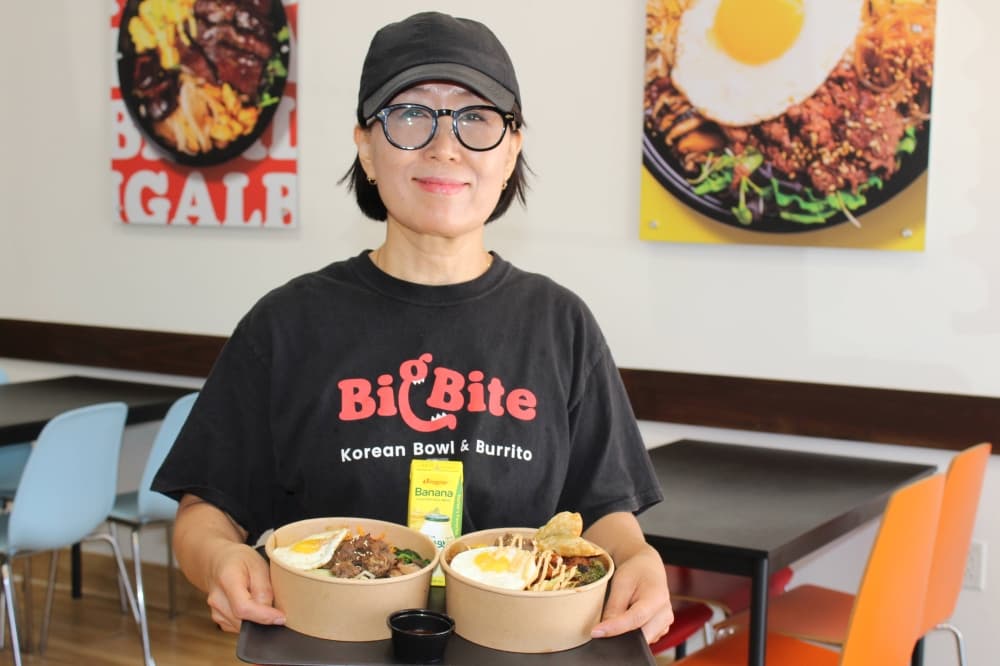Female wearing shirt with Big Bite branding while holding a tray of food. 