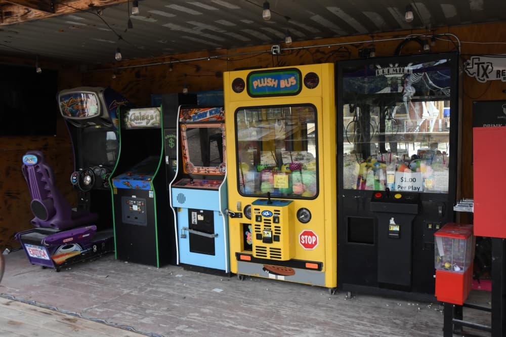 The image shows arcade games in a shed-like structure. 