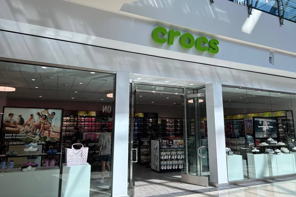 Exterior of a store in a mall with Crocs signage. 