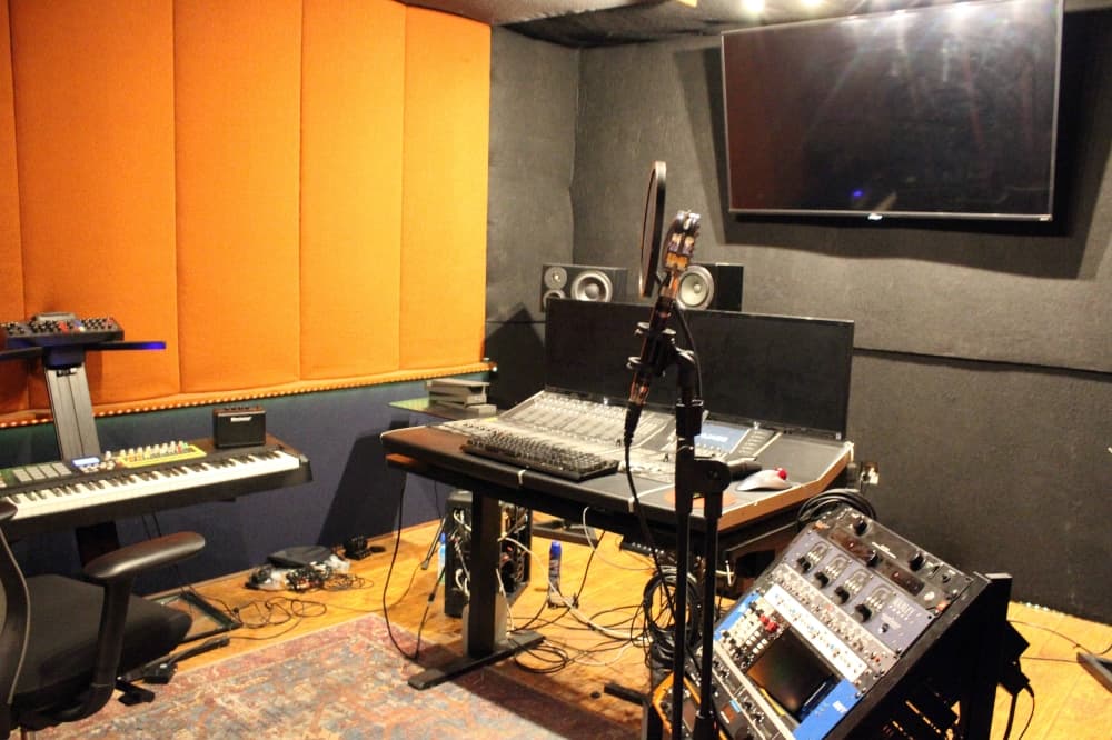 Recording studio featuring sound board, keyboard, microphone and amplifier. 