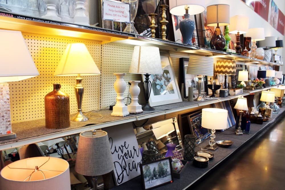 A variety of lamps and household decor items on shelves in a store. 