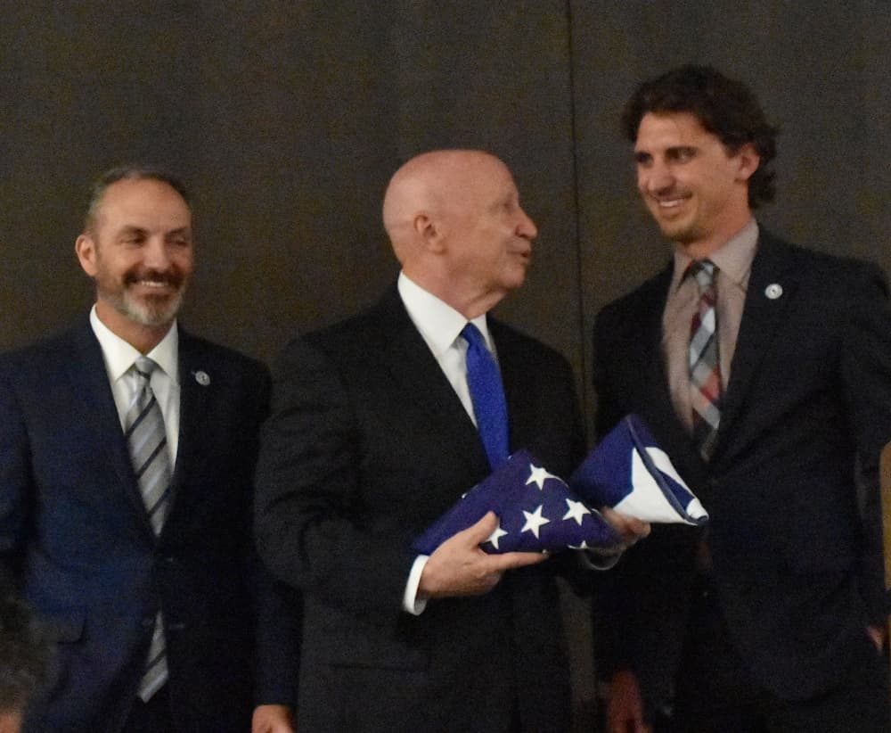 Three men are gathered at a podium