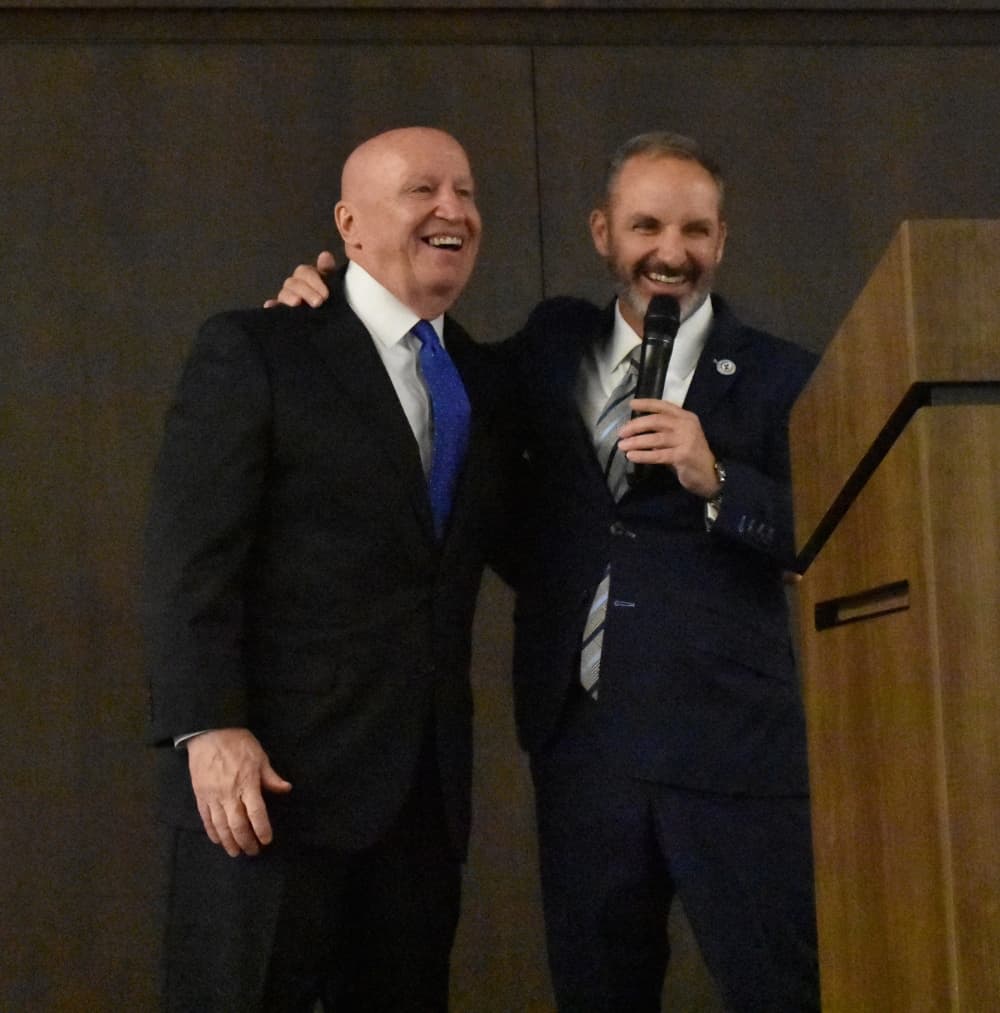 Two men smile at a podium