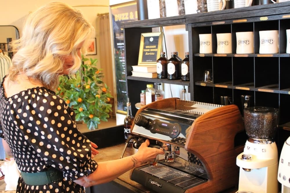 A woman making a latte with an espresso machine.