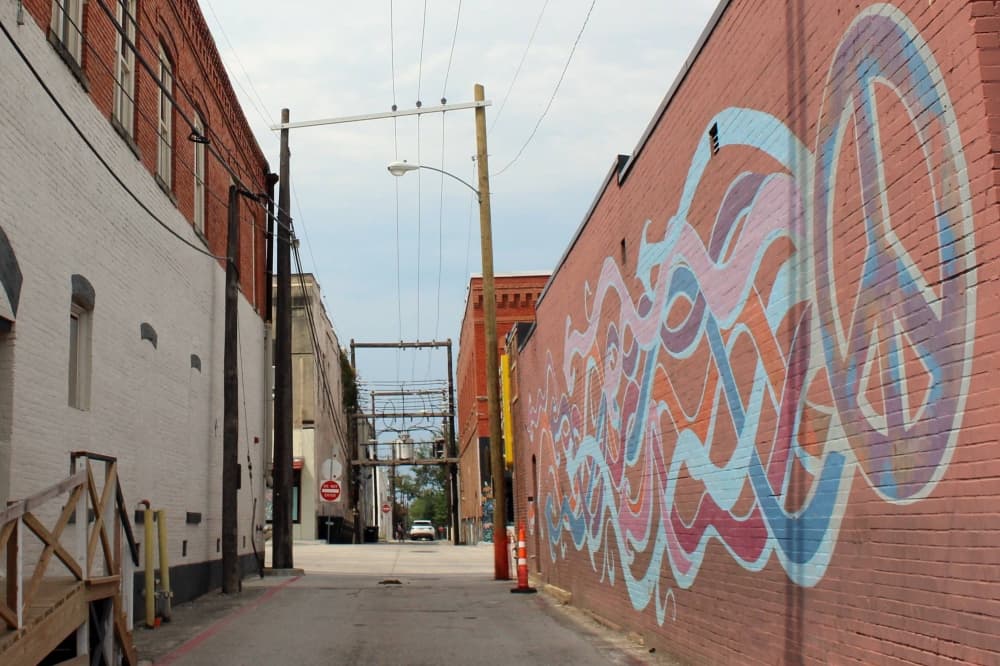 Peace sign and colorful waves mural on a brick wall. 
