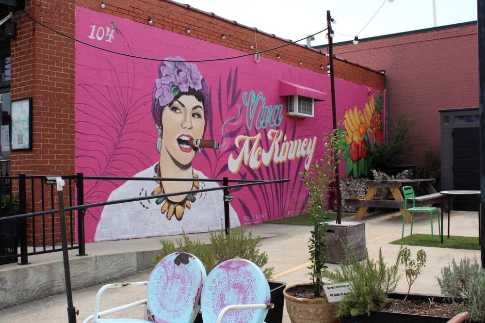 Pink mural featuring female smoking a cigar. 