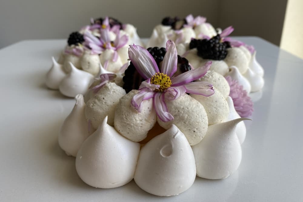 Sivaraju bakes individual pavlovas with mango filling and blackberry compote, topped with fresh blackberries and edible flowers. (Katlynn Fox/ Community Impact)