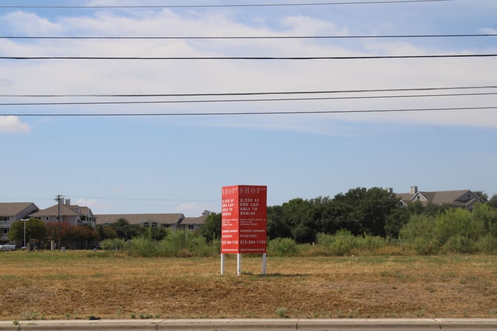 Pictured is an empty lot with a red sign.