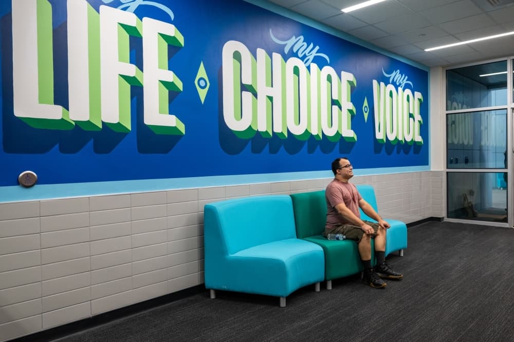Denise Geiger Compass Center student sitting under a banner 