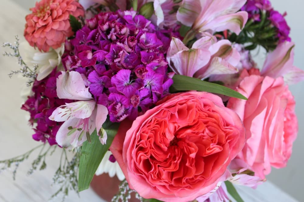 Floral arrangement featuring purple and pink flowers and greenery. 