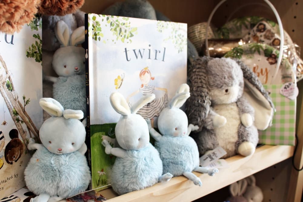 Children's book and stuffed animals displayed on a shelf. 