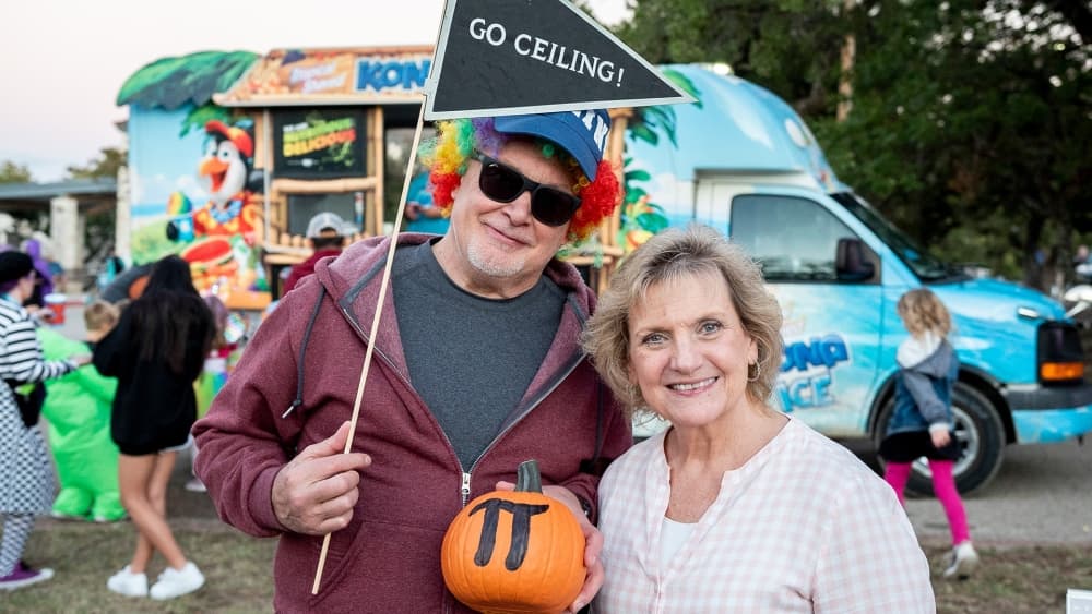 An image of two people holding a pumpkin at a previous year's event. 
