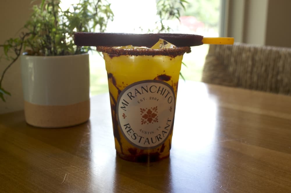 There are many flavors of aguas frescas available at Mi Ranchito, inluding mango, watermelon and piña. Pictures is the mango agua fresca with tajin and chamoy, which can be added for a small charge. (Sienna Wight/Community Impact)